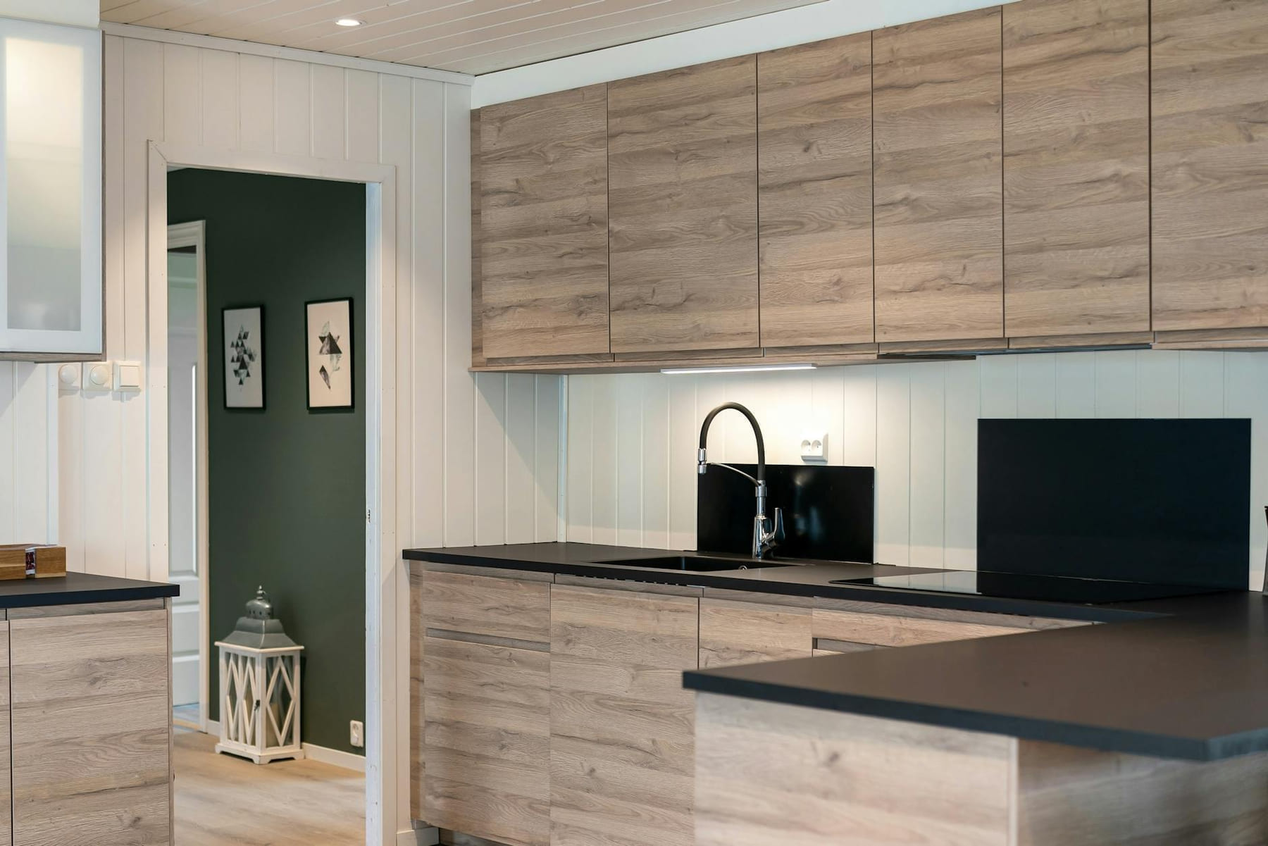 Sleek kitchen interior featuring wooden cabinets and black countertops. on Hammer & Home
