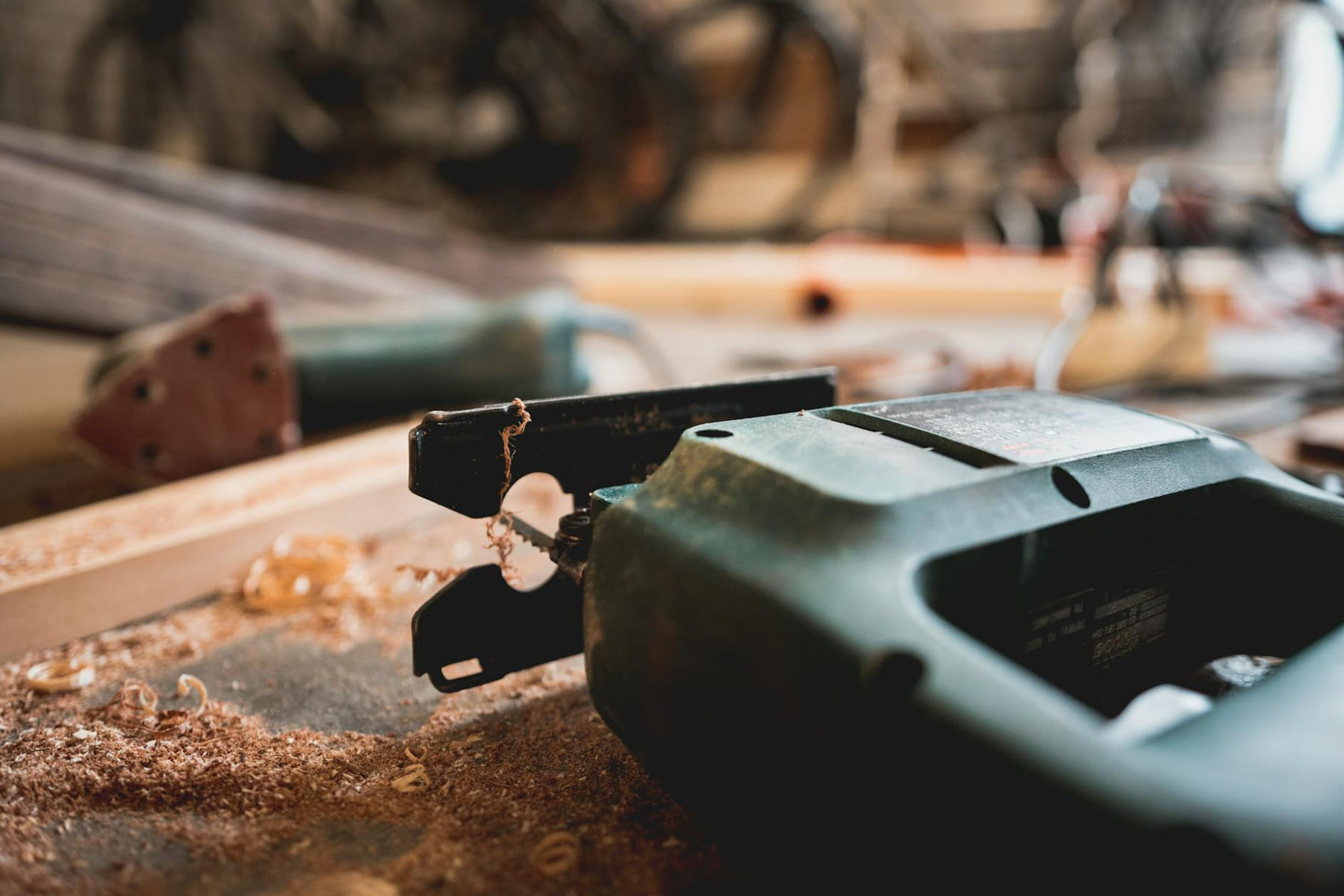 Detailed view of a jigsaw and wood shavings on a workshop table. on Hammer & Home