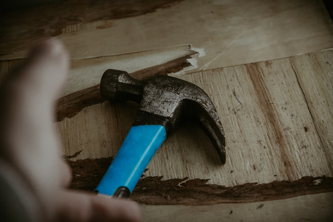 a hammer with a blue handle on a piece of wood on Hammer & Home