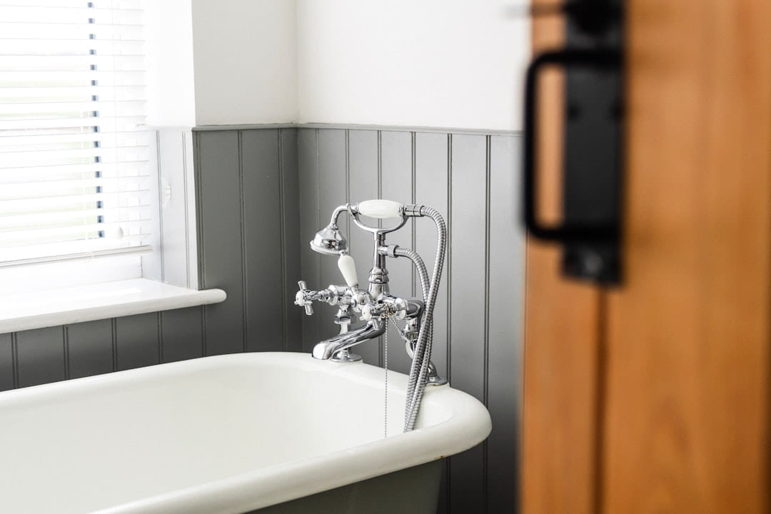 a bathroom with a claw foot tub and a wooden door on Hammer & Home