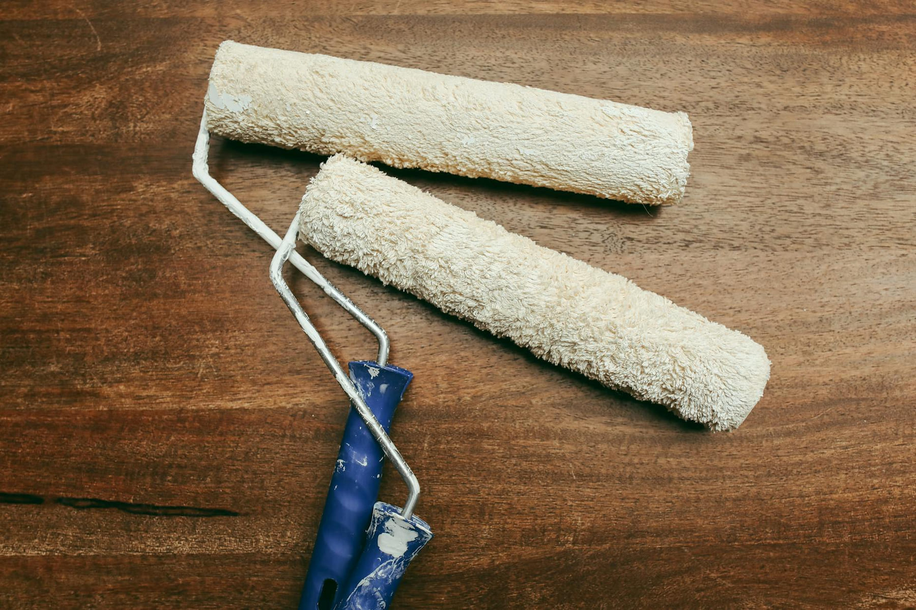 Two paint rollers over a wooden surface, perfect for home renovation concepts. on Hammer & Home