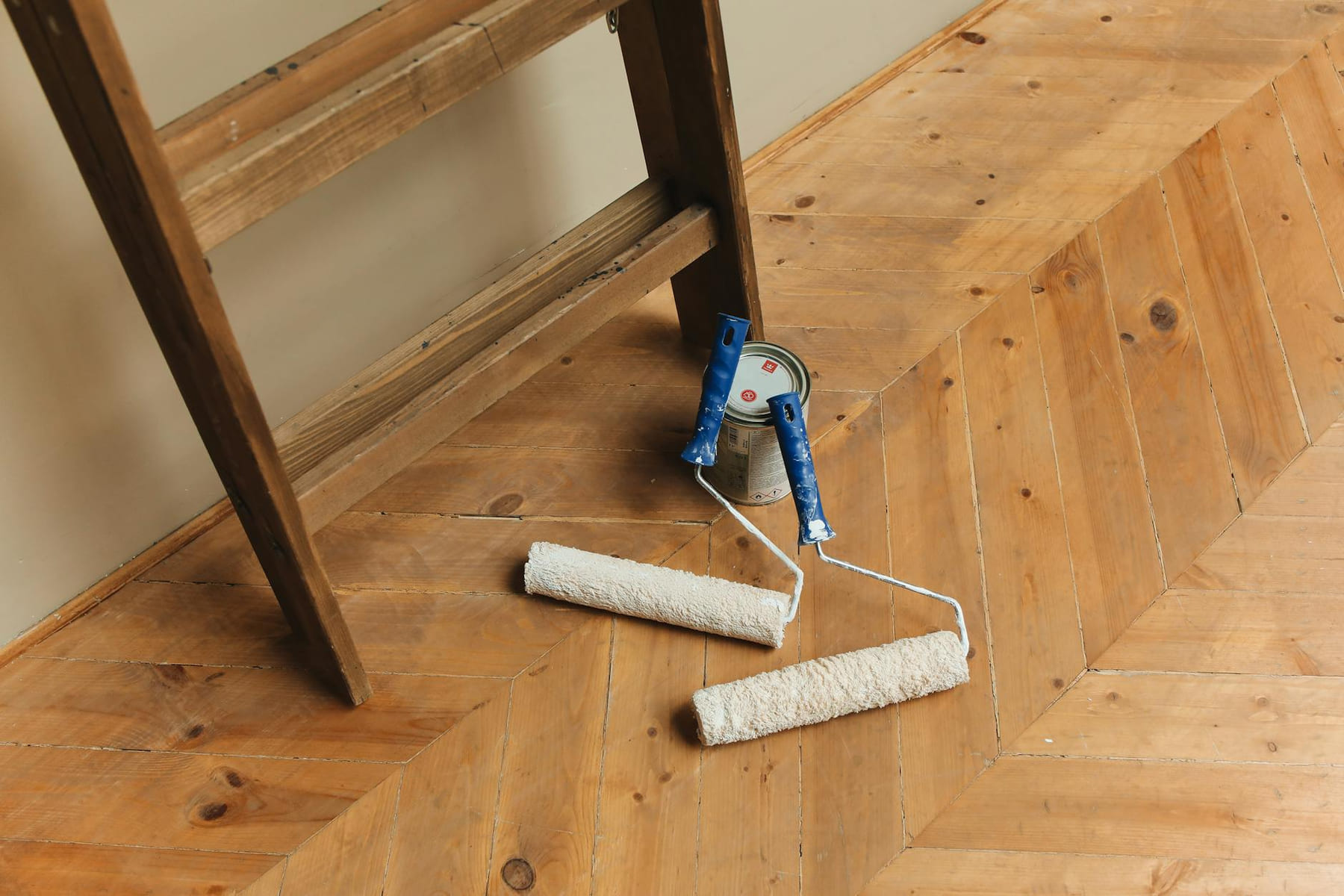 Paint rollers and ladder on a wooden floor, perfect for DIY renovation projects. on Hammer & Home