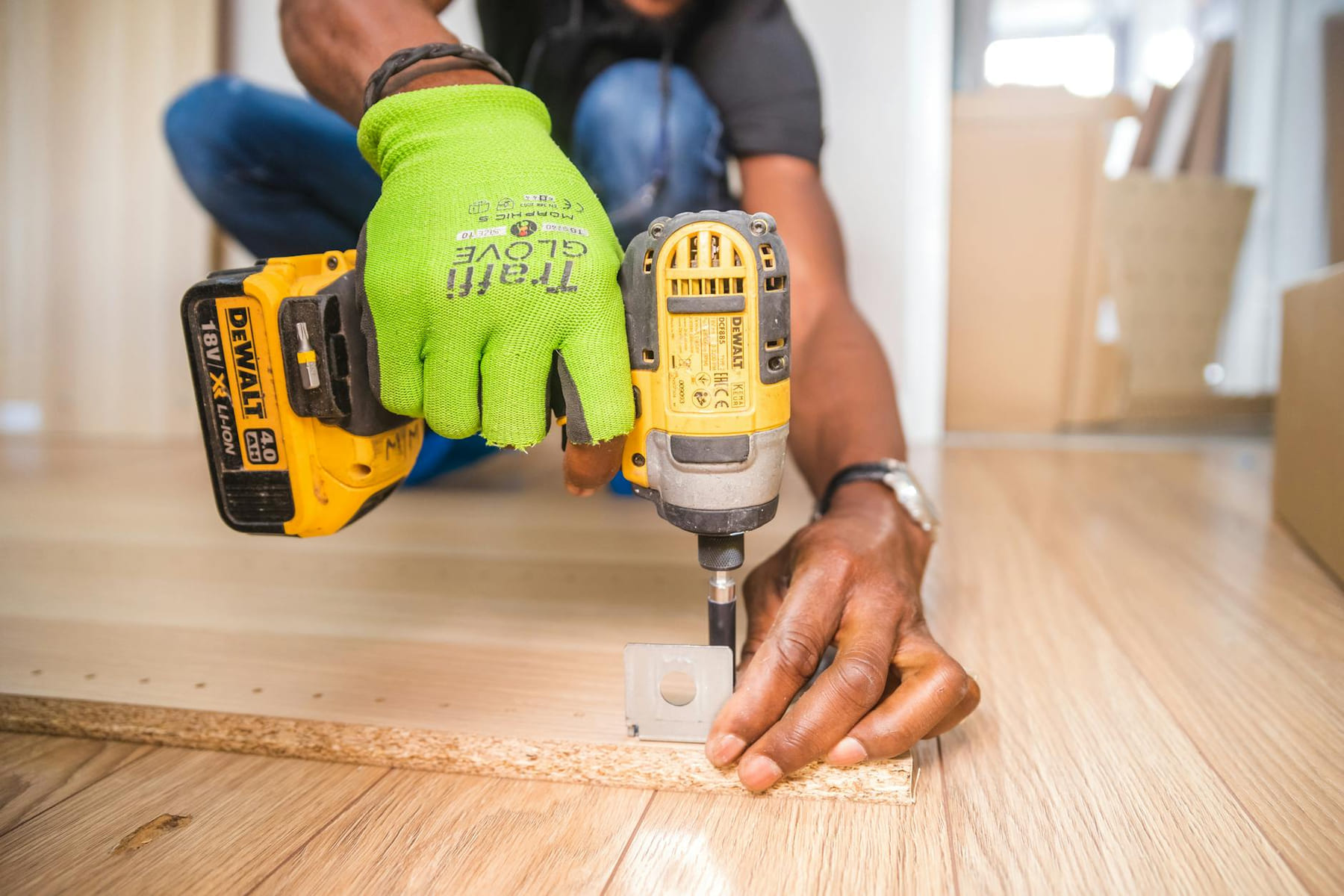 Man using a power drill for home improvement on a wooden floor with precision. on Hammer & Home