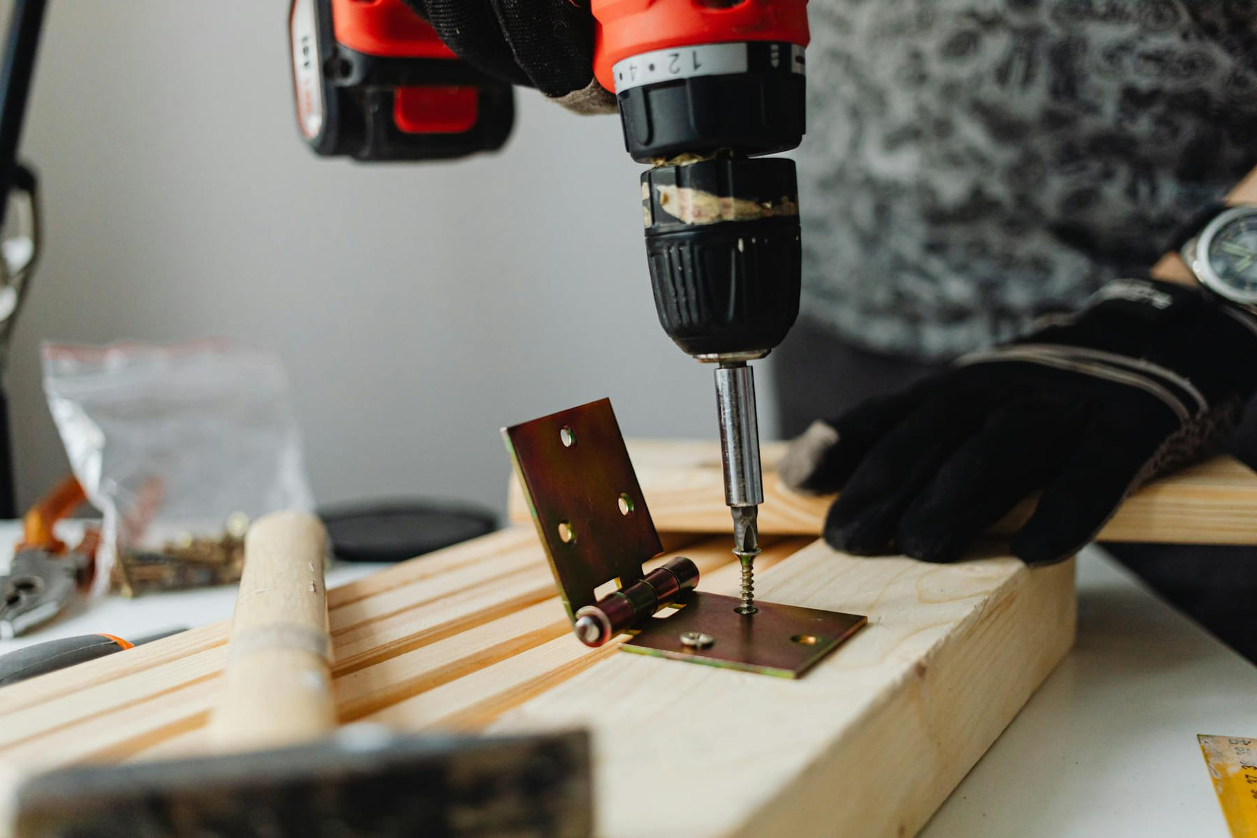 Close-up of a skilled carpenter using a power drill on wood in a workshop. on Hammer & Home