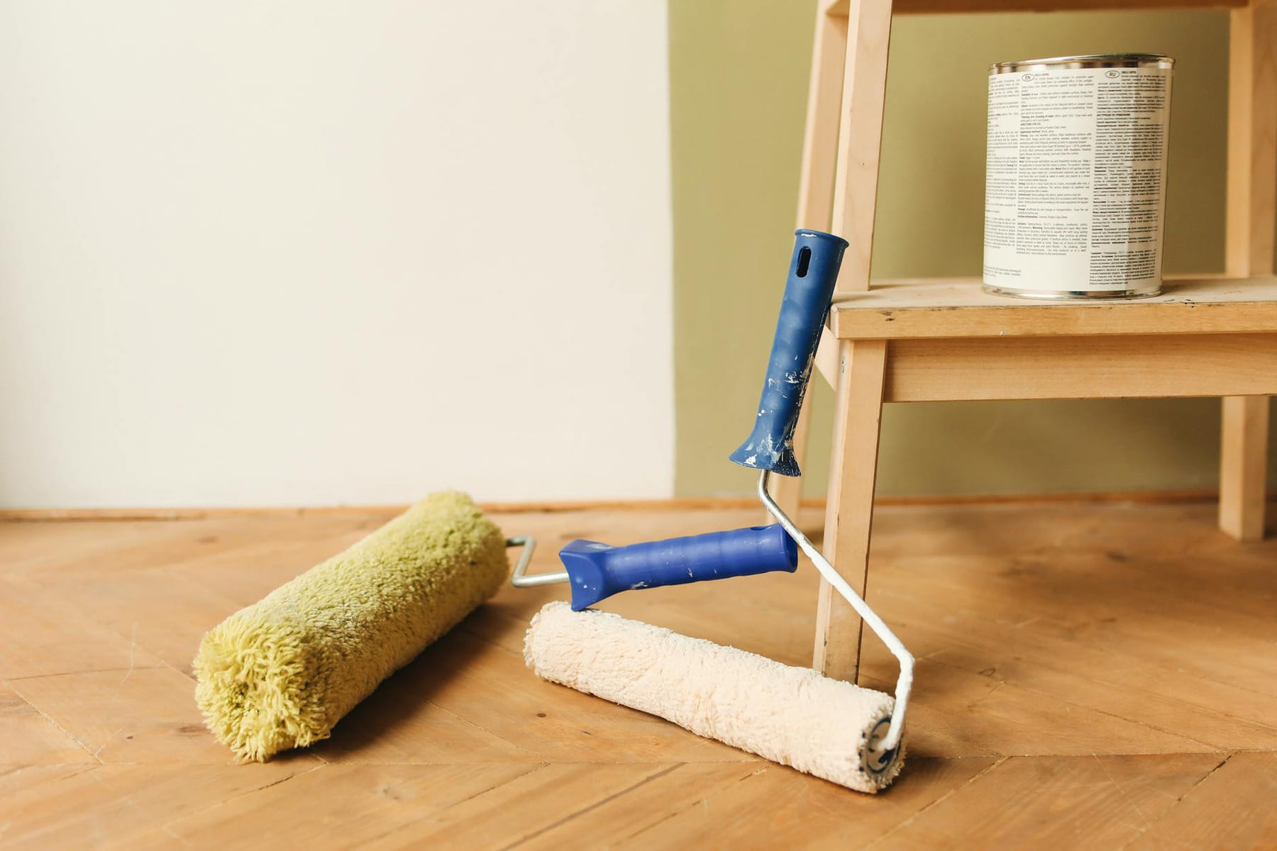 Paint rollers on wooden floor surface next to a can, ready for home renovation. on Hammer & Home