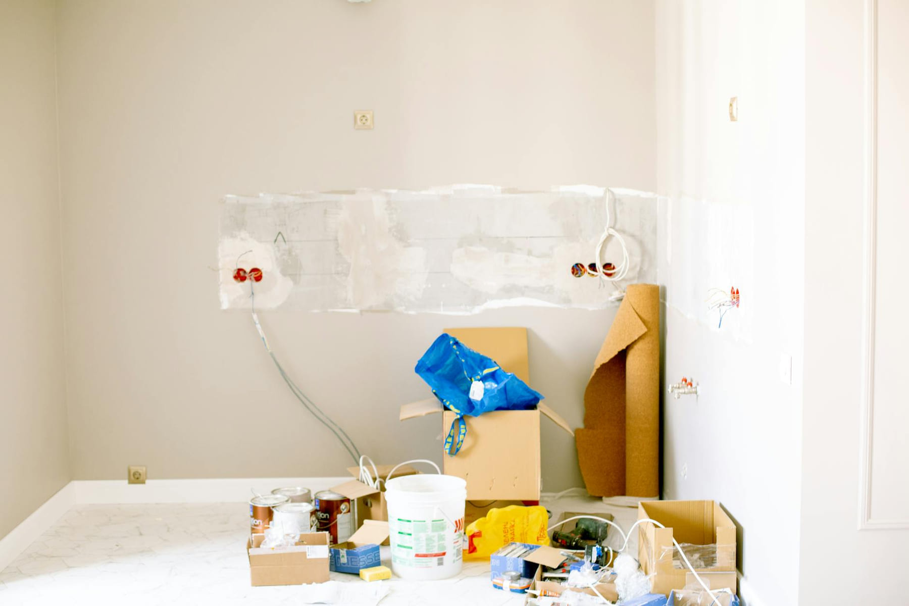 A room undergoing renovation with tools, supplies, wiring, and paint cans scattered around. on Hammer & Home