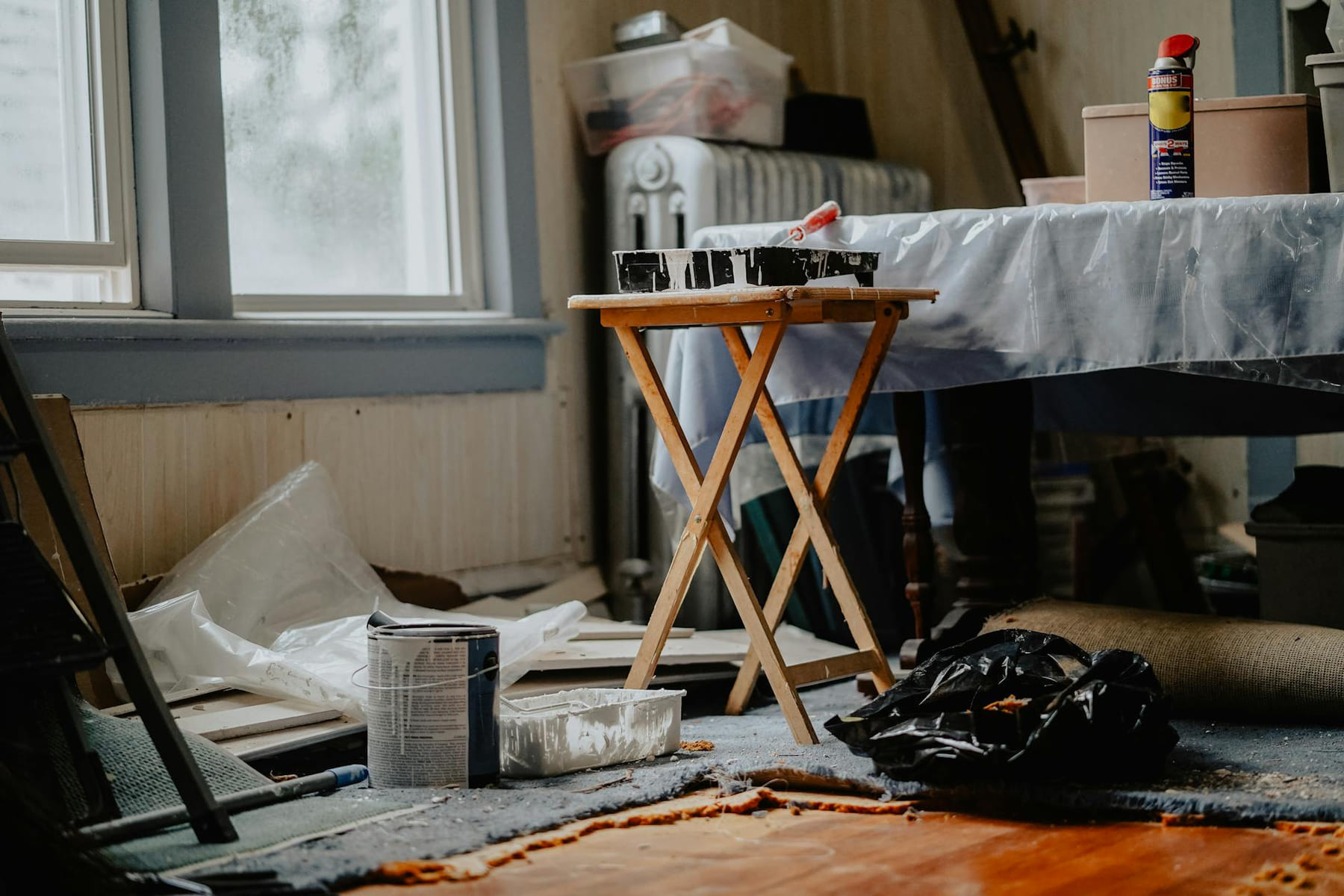 Interior view of a home renovation with paint supplies on a wooden table. on Hammer & Home
